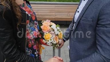 一对相爱的情侣在浪漫的约会中的手。背景是一束美丽的花束。